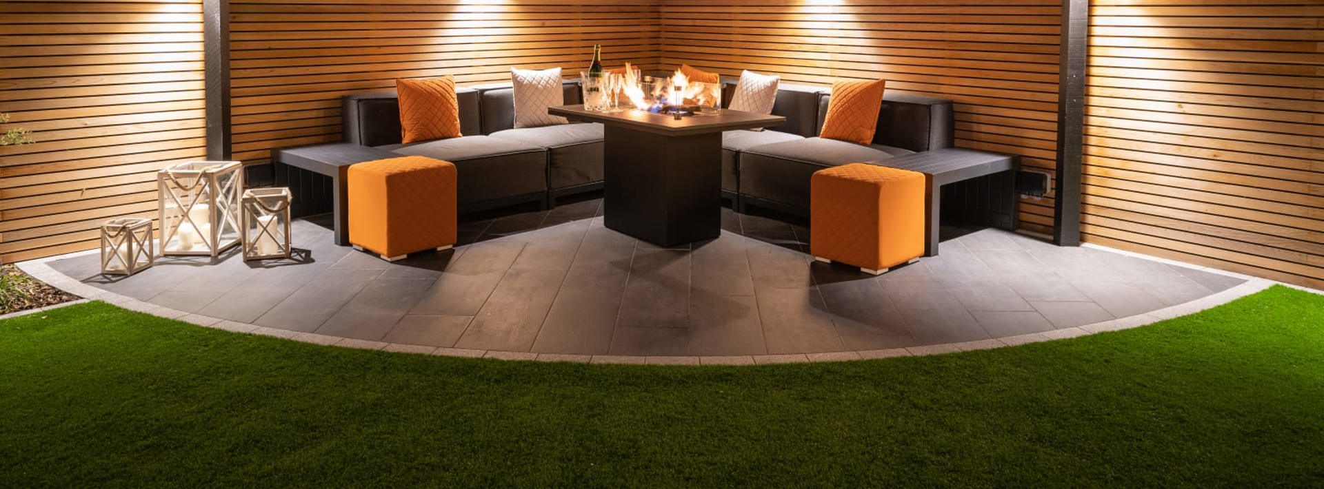 Marshalls Arrento paving laid in a garden with modern grey garden seating at night