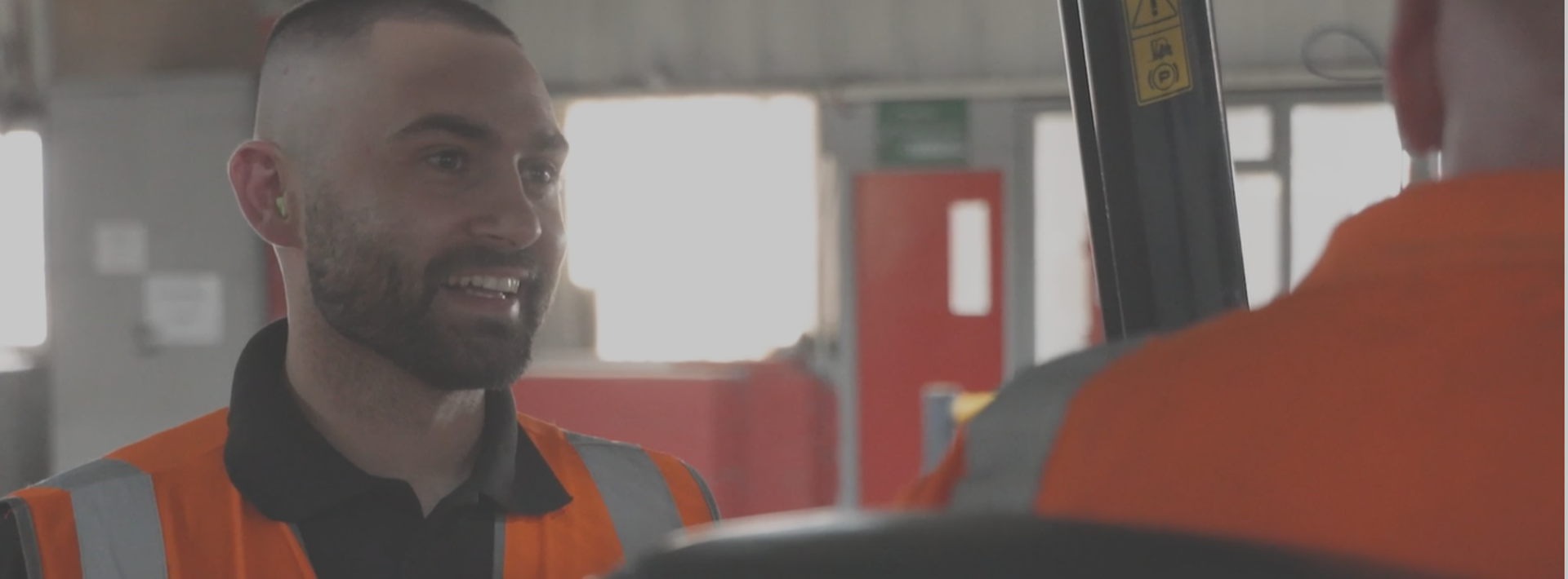 Staff in high vis workwear talking to each other whilst on machinery