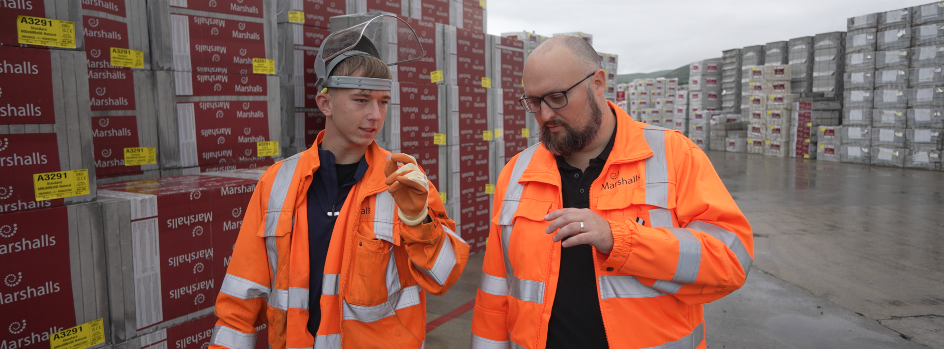 Two members of staff walking together and talking wearing orange Marshalls workwear