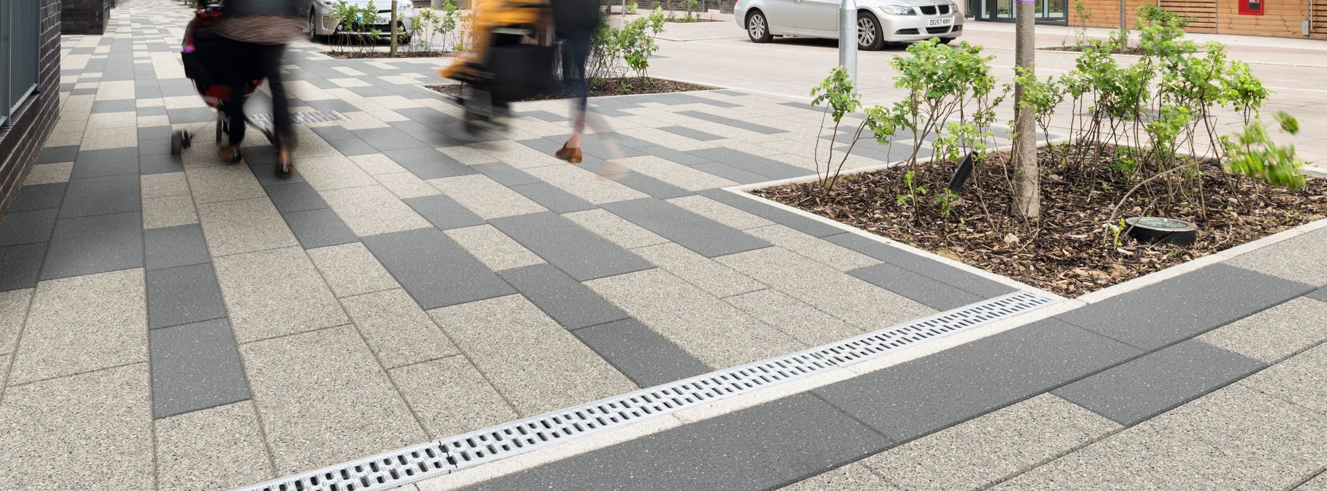 Two members of the public walking with pushchairs over Marshalls Conservation X silver and blue grey paving