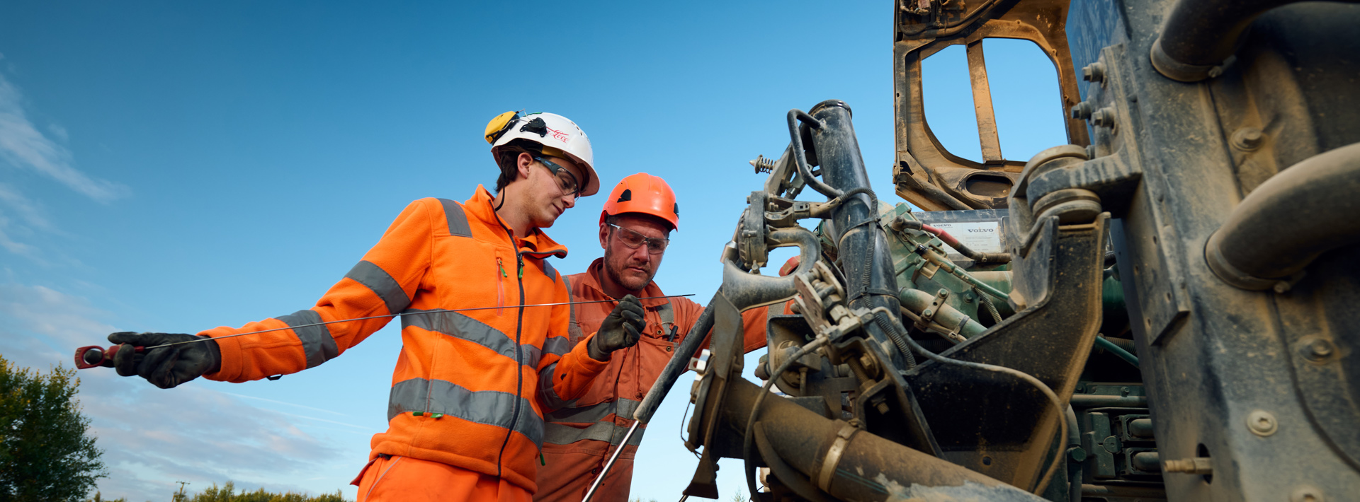 Staff in high vis orange workwear looking at machinery